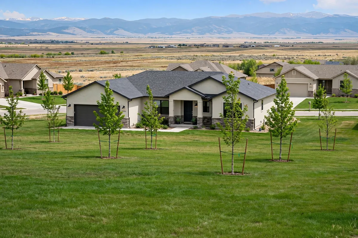 Ranch home in Brighton with young trees, open prairie, and distant mountains behind it