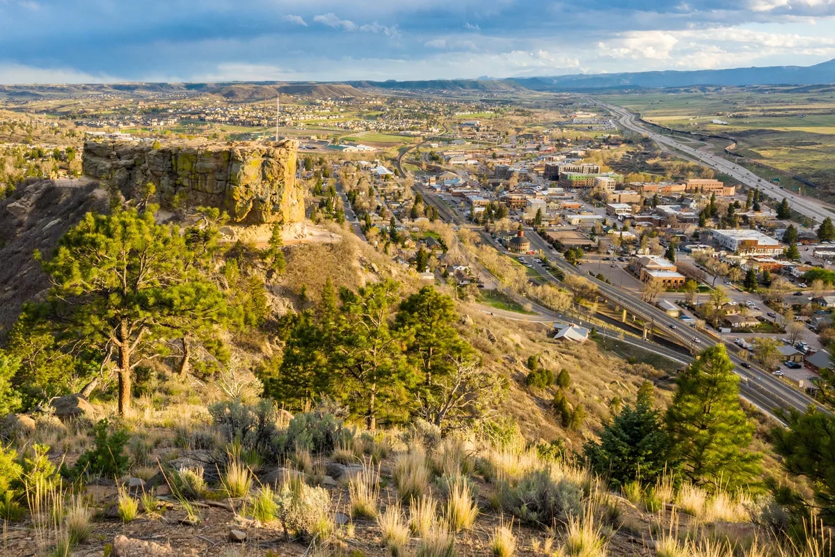 The castle-shaped rock butte rising above Castle Rock with downtown and a highway below it