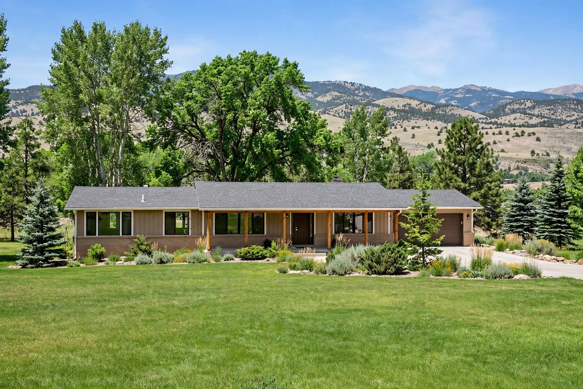 Ranch home in Littleton with a wide lawn, mature trees, and foothills behind it