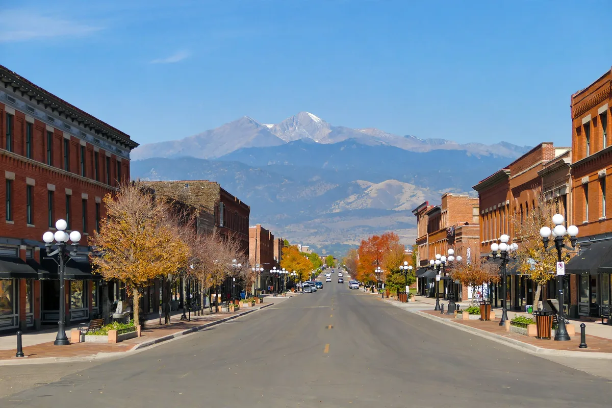 Historic brick storefronts on a Longmont main street with Longs Peak behind the city