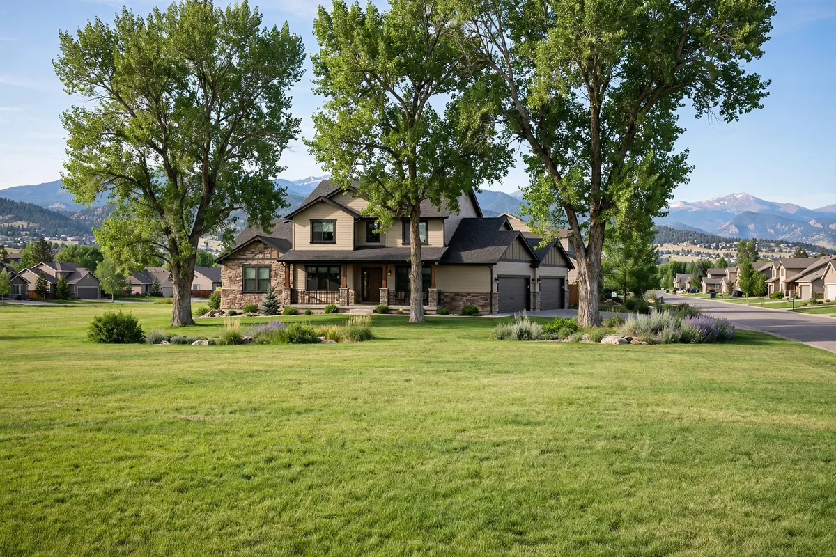 Two-story home in Longmont with a wide lawn, large cottonwood trees, and mountains behind it