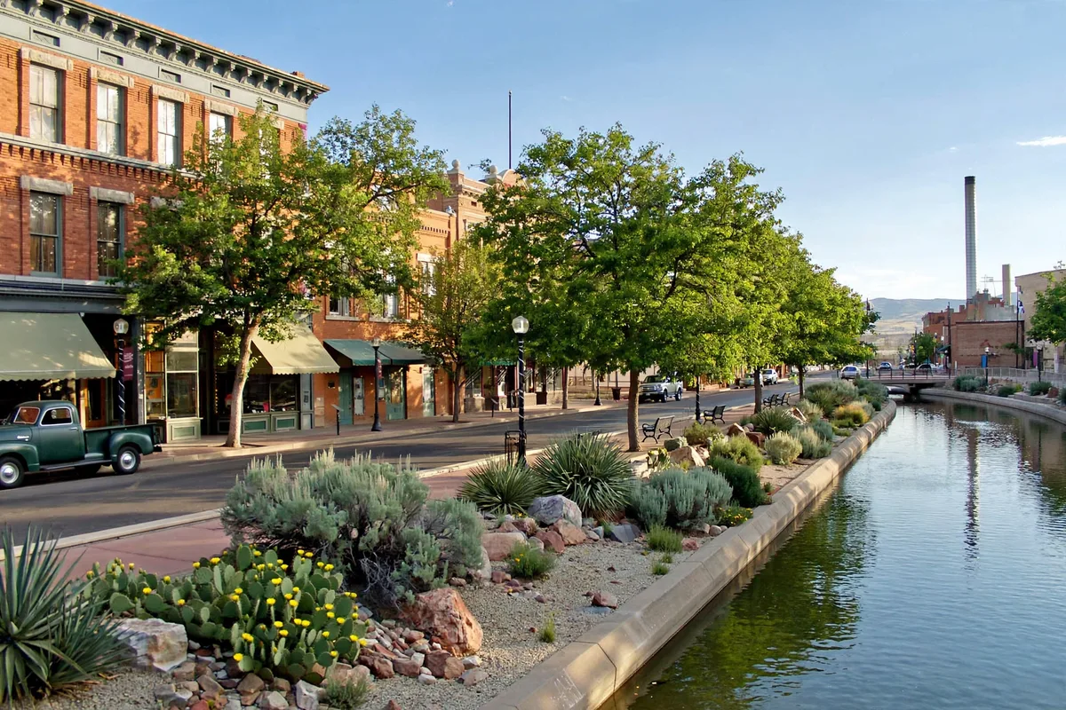 Historic brick buildings beside the riverwalk canal in downtown Pueblo with desert plants along the water
